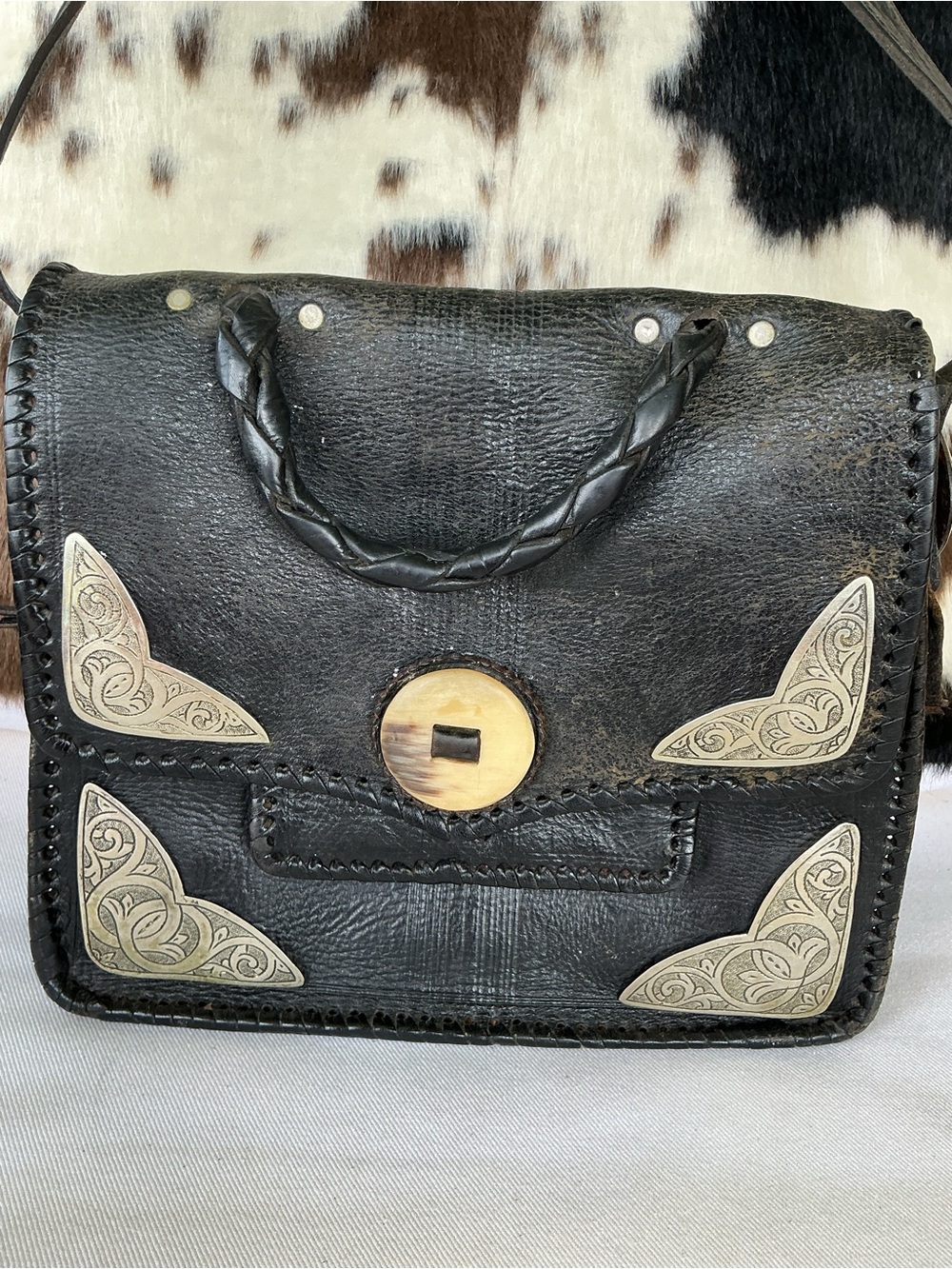 Black Leather Shoulder Bag with Braided Handle and Decorative Metal Corners